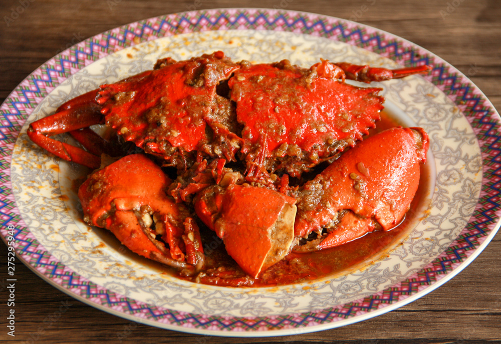 Crab in Padang sauce or Padang crab (Indonesian: Kepiting saus Padang) on wood background.