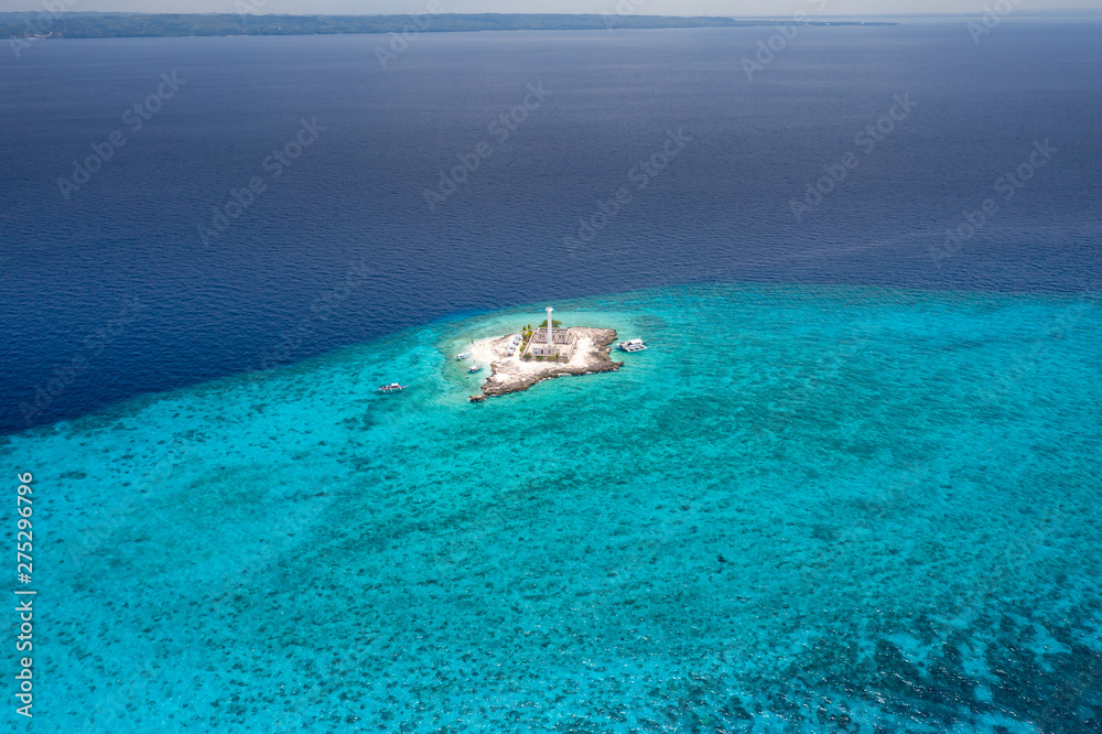 Aerial drone view of a lighthouse on a tiny tropical island surrounded by coral reef and deep water (Capitancillo Island, Cebu, Philippines) Aerial drone view of a lighthouse on a tiny tropical island surrounded by coral reef and deep water (Capitancillo Island, Cebu, Philippines)