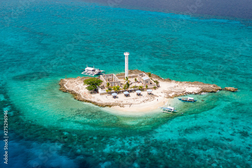 Aerial drone view of a lighthouse on a tiny tropical island surrounded by coral reef and deep water (Capitancillo Island, Cebu, Philippines)