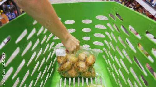 First-person view: woman puts fresh goods in the shopping trolley, which is moving through aisles of supermarket, sale and shopping concept