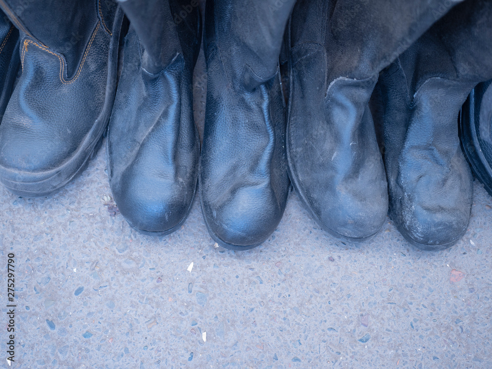 Boots stand in a row, tight to each other. Asphalt background. Boots stand in a row, tight to each other. Asphalt background.