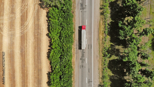 Aerial. Red truck on a road between fields. Transport logistics background.