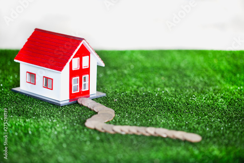 Small red and white houses on green grass.House on green grass. Give the route as a coin.