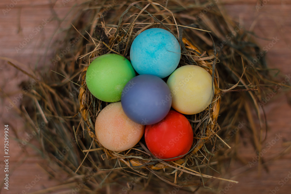 Easter eggs in a basket decorated with straw on a wooden rustic background Easter eggs in a basket decorated with straw on a wooden rustic background