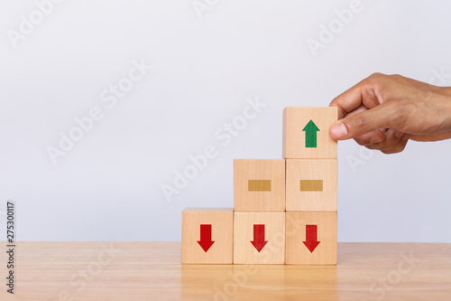 Hand arranging wooden cube stack with arrows pointing up on white background. Concept of growth and success or rising successful development and business development in the future