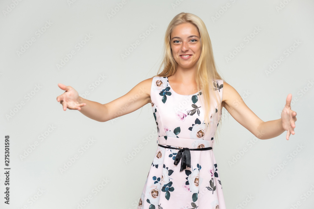 Portrait of a cute beautiful pretty woman girl with long beautiful hair on a white background in a pink dress with a pattern. Shows many different emotions, smiles and talks. Made in a studio. Portrait of a cute beautiful pretty woman girl with long beautiful hair on a white background in a pink dress with a pattern. Shows many different emotions, smiles and talks. Made in a studio.