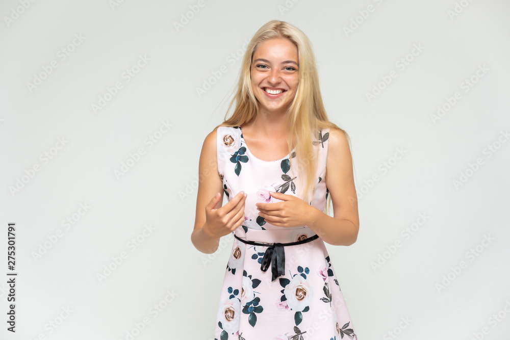 Portrait of a cute beautiful pretty woman girl with long beautiful hair on a white background in a pink dress with a pattern. Shows many different emotions, smiles and talks. Made in a studio. Portrait of a cute beautiful pretty woman girl with long beautiful hair on a white background in a pink dress with a pattern. Shows many different emotions, smiles and talks. Made in a studio.