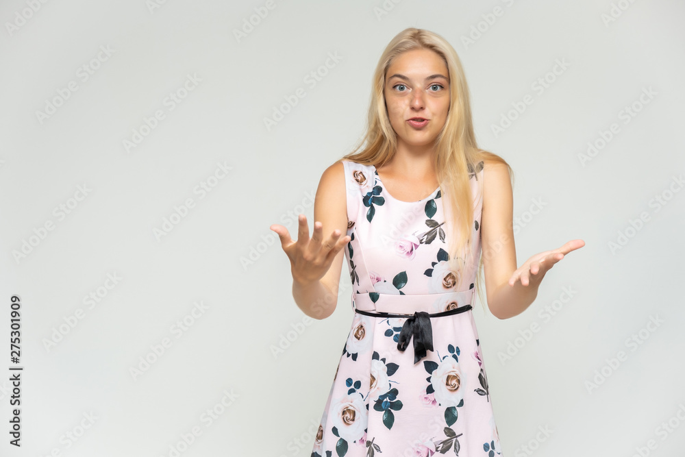 Portrait of a cute beautiful pretty woman girl with long beautiful hair on a white background in a pink dress with a pattern. Shows many different emotions, smiles and talks. Made in a studio. Portrait of a cute beautiful pretty woman girl with long beautiful hair on a white background in a pink dress with a pattern. Shows many different emotions, smiles and talks. Made in a studio.