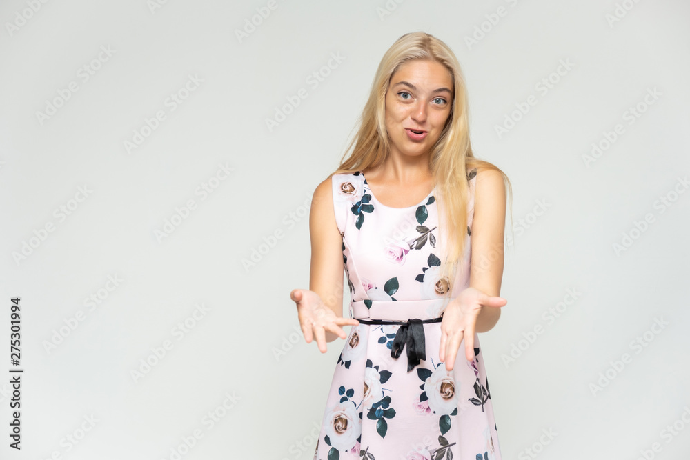 Portrait of a cute beautiful pretty woman girl with long beautiful hair on a white background in a pink dress with a pattern. Shows many different emotions, smiles and talks. Made in a studio. Portrait of a cute beautiful pretty woman girl with long beautiful hair on a white background in a pink dress with a pattern. Shows many different emotions, smiles and talks. Made in a studio.