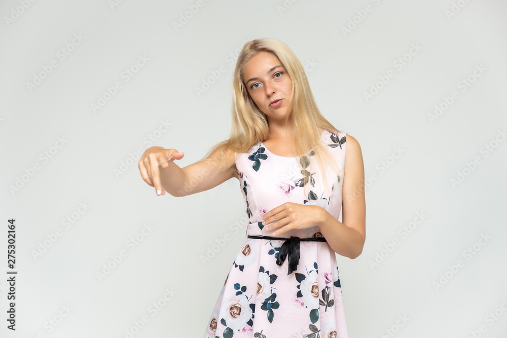 Portrait of a cute beautiful pretty woman girl with long beautiful hair on a white background in a pink dress with a pattern. Shows many different emotions, smiles and talks. Made in a studio. Portrait of a cute beautiful pretty woman girl with long beautiful hair on a white background in a pink dress with a pattern. Shows many different emotions, smiles and talks. Made in a studio.