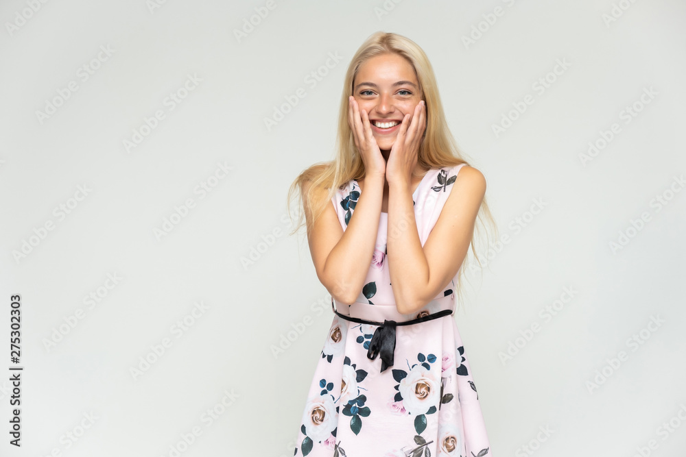 Portrait of a cute beautiful pretty woman girl with long beautiful hair on a white background in a pink dress with a pattern. Shows many different emotions, smiles and talks. Made in a studio. Portrait of a cute beautiful pretty woman girl with long beautiful hair on a white background in a pink dress with a pattern. Shows many different emotions, smiles and talks. Made in a studio.