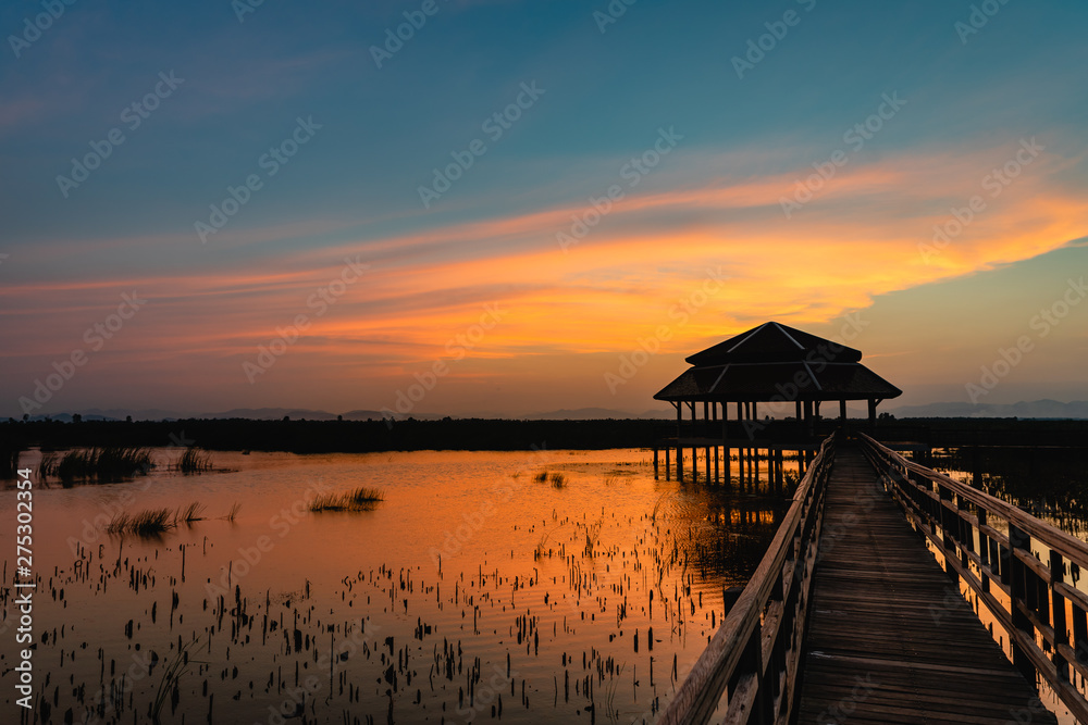 Sunset with wooden bridge and pavilion in the lake with cloud and twilight sky at Khao Sam Roi Yot National Park, Thailand.