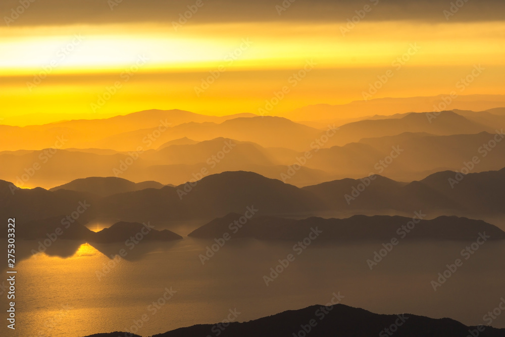 Mountains and the sea, sunset, sky in pastel colors, light haze, blur.