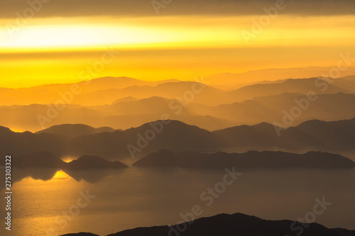 Mountains and the sea, sunset, sky in pastel colors, light haze, blur.