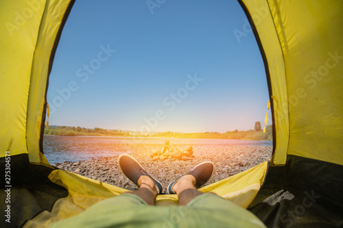 Tourist is in a tent camp, overlooking the lake. the concept of active rest of life. stone beach. yellow tent. bright sunny day