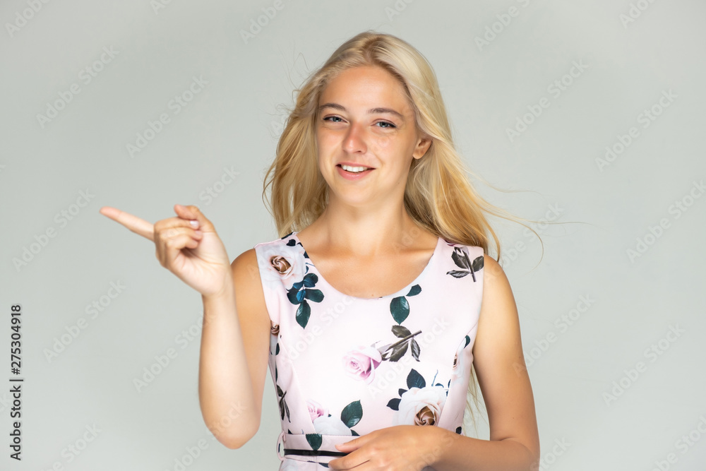 Portrait of a cute beautiful pretty woman girl with long beautiful hair on a white background in a pink dress with a pattern. Shows many different emotions, smiles and talks. Made in a studio. Portrait of a cute beautiful pretty woman girl with long beautiful hair on a white background in a pink dress with a pattern. Shows many different emotions, smiles and talks. Made in a studio.
