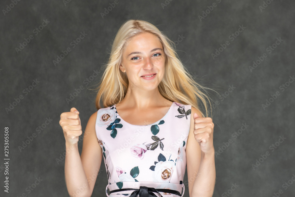 Portrait of a cute beautiful pretty woman girl with long beautiful hair on a dark gray background in a pink dress with a pattern. Shows a lot of different emotions, smiling, talking. Made in a studio. Portrait of a cute beautiful pretty woman girl with long beautiful hair on a dark gray background in a pink dress with a pattern. Shows a lot of different emotions, smiling, talking. Made in a studio.