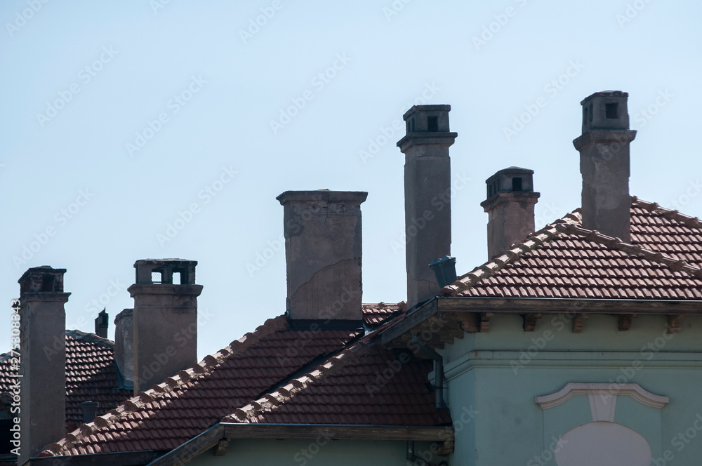House roofs and chimneys on clear blue sky background