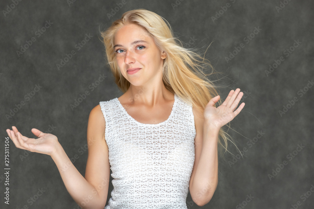 Portrait of a cute beautiful pretty woman girl with long beautiful hair on a dark gray background in a white sweater with a pattern. Shows many different emotions, smiles and talks. Made in a studio. Portrait of a cute beautiful pretty woman girl with long beautiful hair on a dark gray background in a white sweater with a pattern. Shows many different emotions, smiles and talks. Made in a studio.