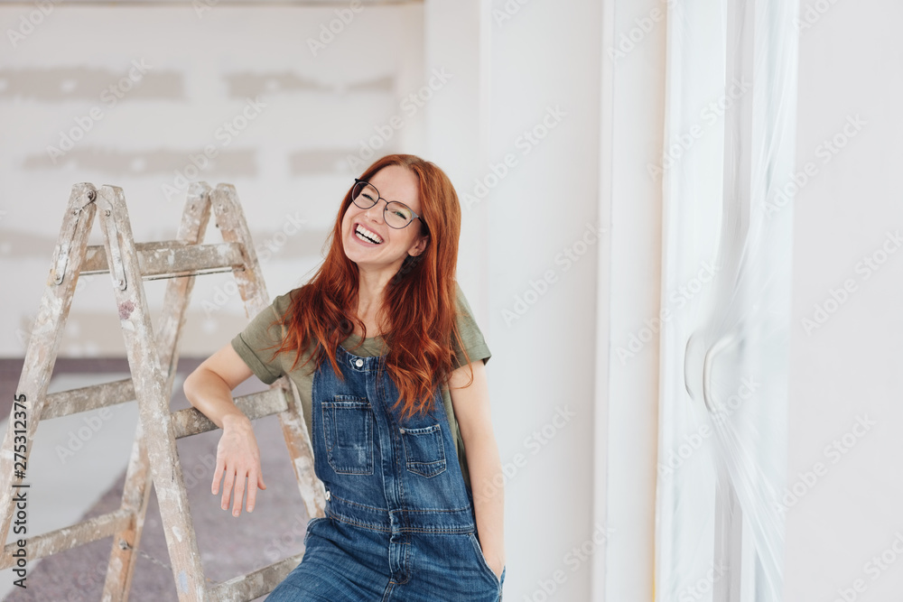 lachende Frau lehnt an einer Leiter auf der Baustelle - obrazy, fototapety, plakaty 