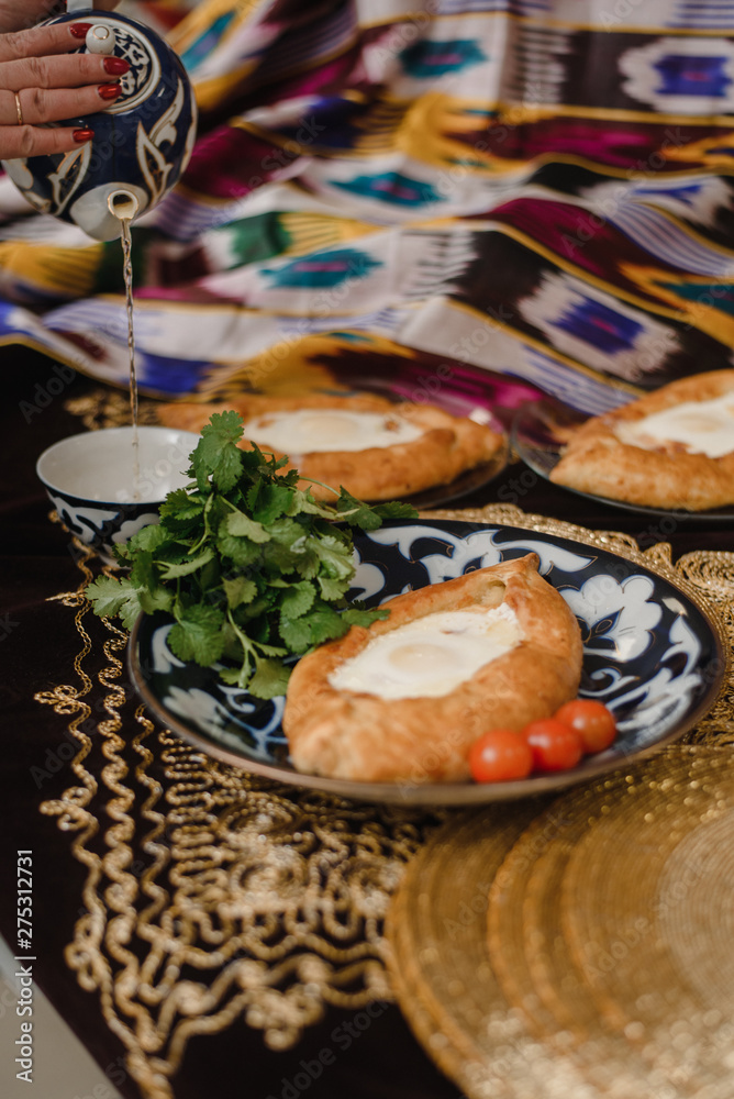 Adjara khachapuri on the eastern table. egg in hot bread on oriental plates is in a restaurant.