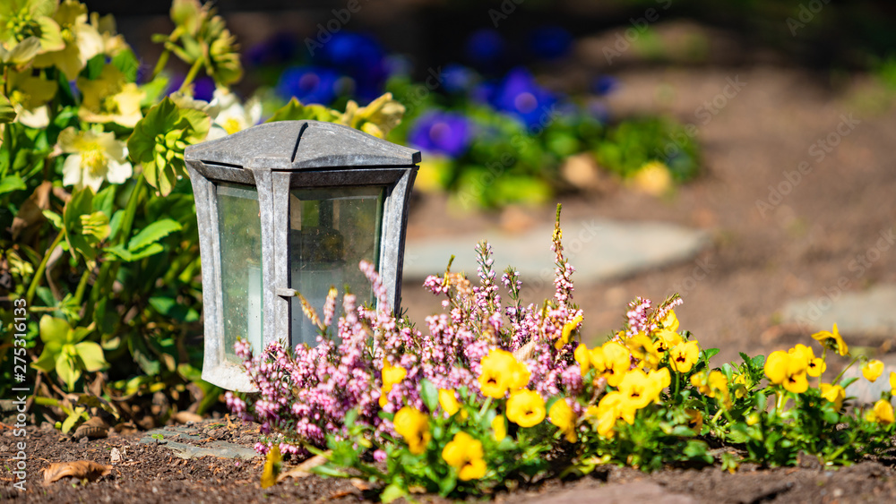 a red candle on the tombstones with flowers a red candle on the tombstones with flowers