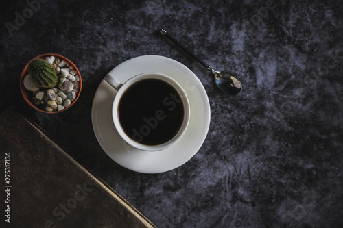 Black coffee in a white coffee cup and cactus placed on a black background