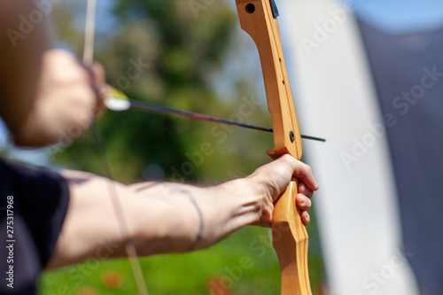 Archer holding wooden bow and aiming at target photo