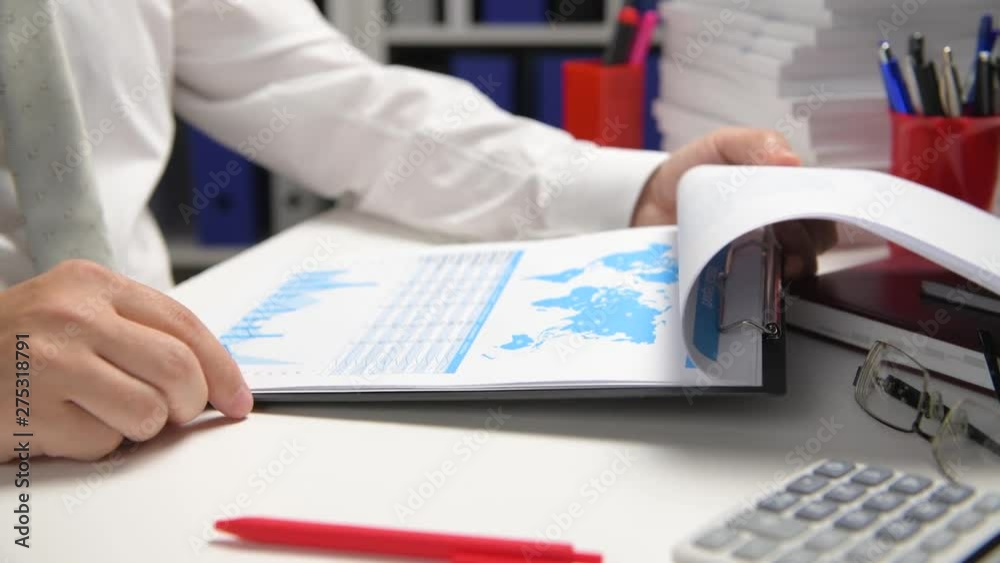 Businessman working and calculating, reads and writes reports. Office employee, table closeup. Business financial accounting concept.