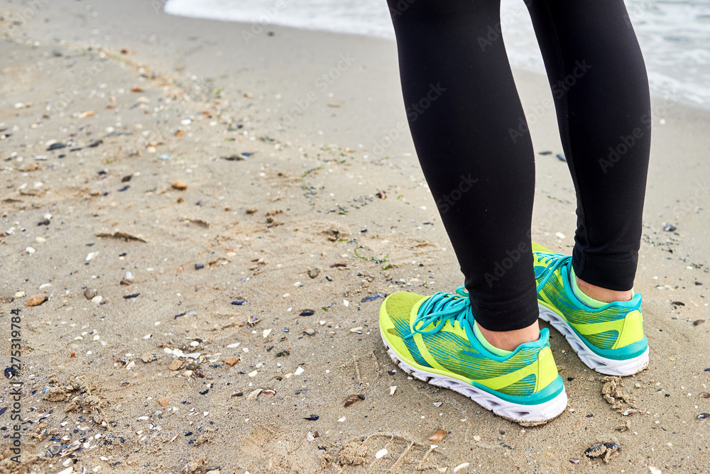 Athletic woman running on sea beach, closeup. Female runner working out at summer morning, copy space. Healthy lifestyle concept Athletic woman running on sea beach, closeup. Female runner working out at summer morning, copy space. Healthy lifestyle concept