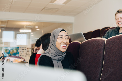 Photography Happy female student sitting with friends in classroom