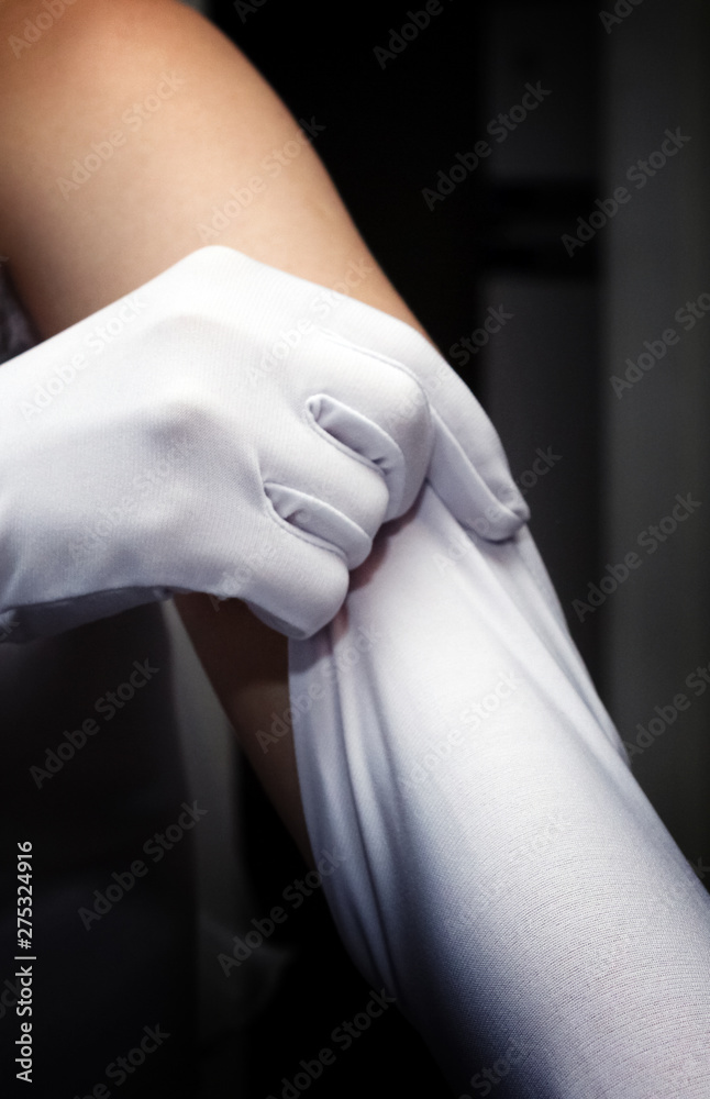 bride puts on white long gloves on her hands