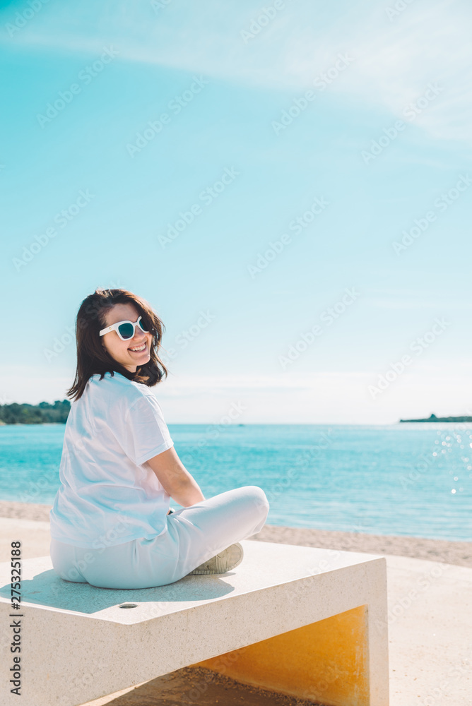 woman sitting at sun lounger at sea beach in white clothes. summer vacation concept woman sitting at sun lounger at sea beach in white clothes. summer vacation concept