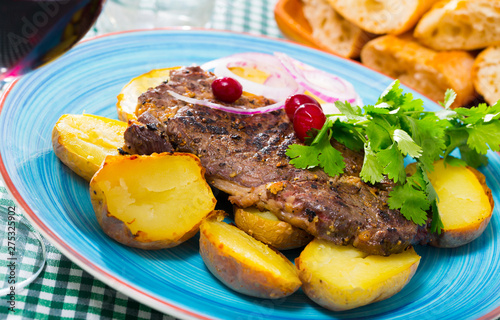 Beef steak with  baked potatoes served at plate with greens