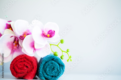 Colored towels and orchid on white table with copy space on bath room background.