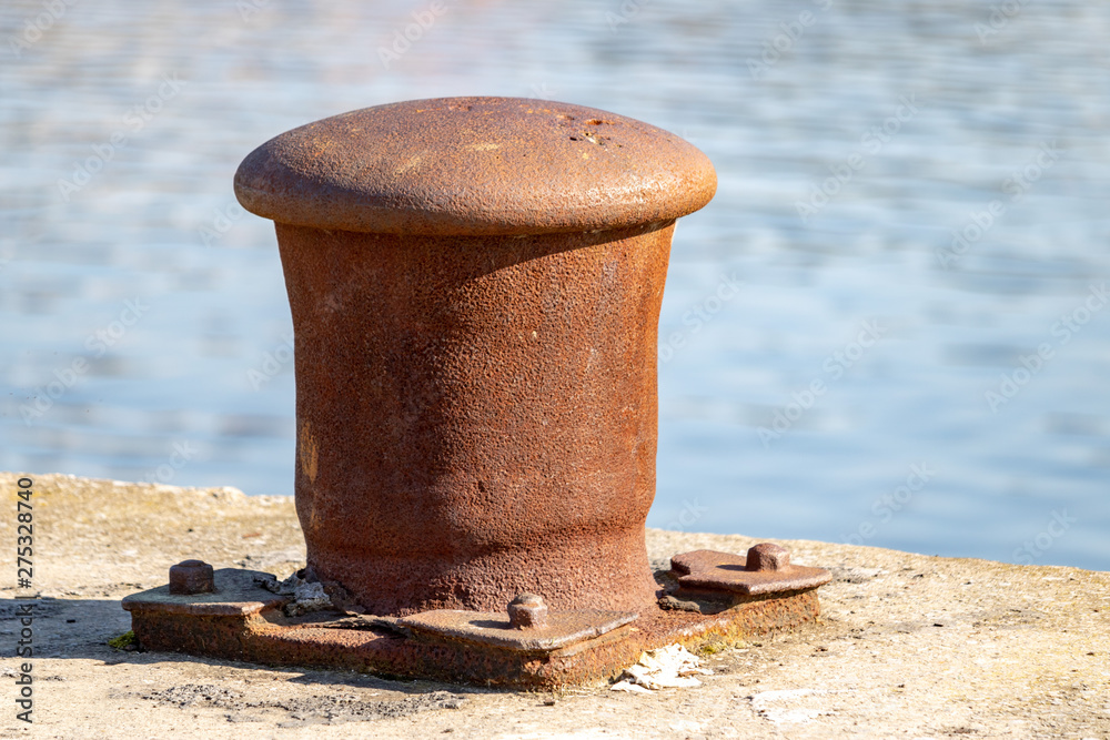 Large rusty bollard on the edge of the river or sea. Close-up photo Water reflections Large rusty bollard on the edge of the river or sea. Close-up photo Water reflections