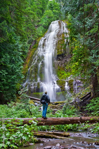 Hiker in forest viewing massive waterfall in Proxy Falls, Oregon