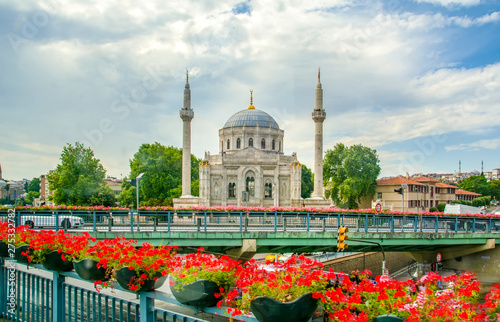 Flowers with Pertevniyal Valide Sultan Mosque, an Ottoman imperial mosque in Istanbul, Turkey. Summer sunny day with blue cloudy sky. photo