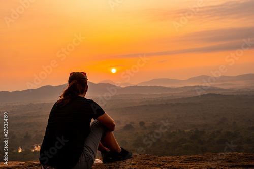 Girl sitting on Pidurangala Rock enjoying sunrise view over Sigiriya rock © Simona