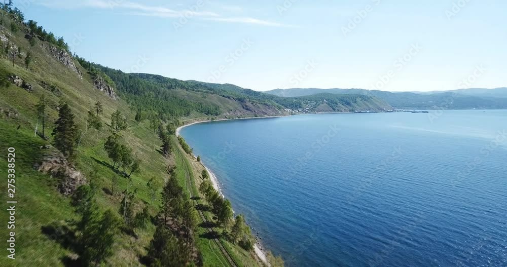 Lake Baikal oldest. Railways Russia Siberia. Mountains pine forest summer sun shines blue water. Beautiful aerial follow above lake. Fast speed aerial drone 4k footage. Lake Baikal oldest. Railways Russia Siberia. Mountains pine forest summer sun shines blue water. Beautiful aerial follow above lake. Fast speed aerial drone 4k footage.