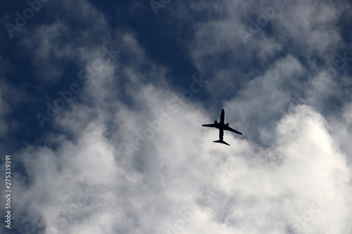 Airplane flying in the sky, air travel. Silhouette of commercial plane taking off on background of white clouds, turbulence concept