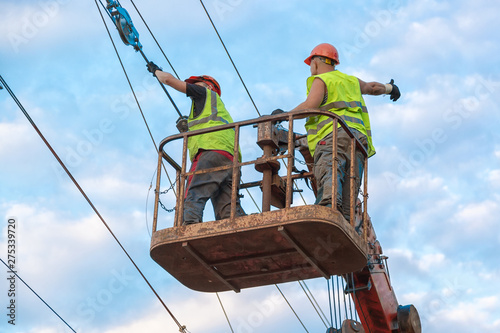 Electrical engineers repairing wire on electric power pole at a railway station
