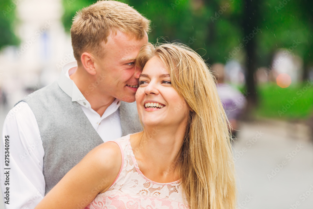 A guy whispers something to the girl's ear and she smiles. park.