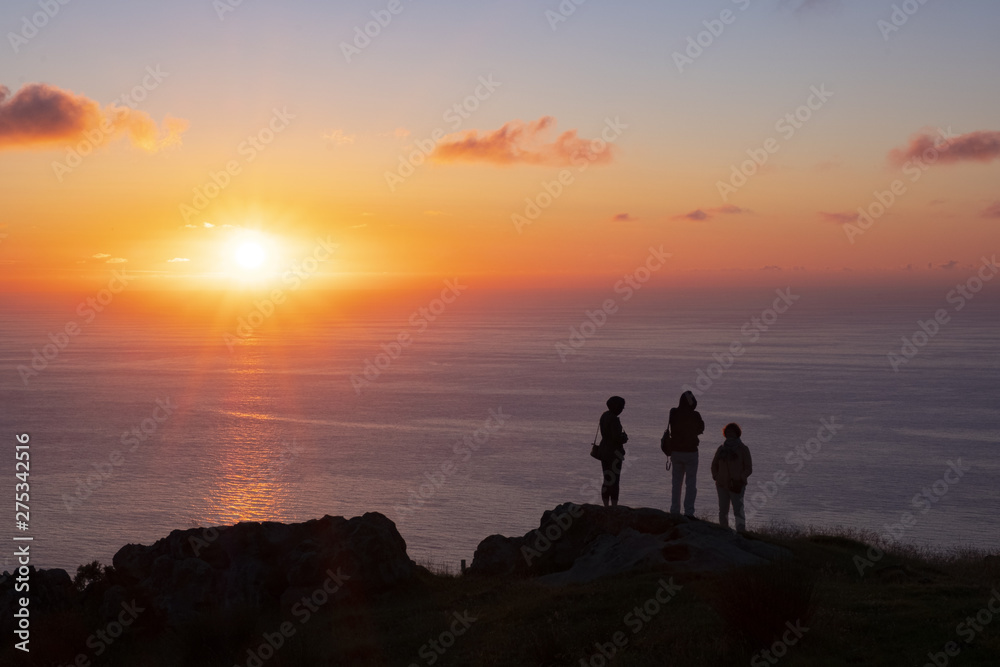 silhouettes of people on top of the mountain with the sun at sunset over the sea, Basque Country