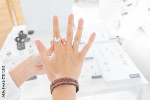 A woman trying on jewelry ring at the shop. Luxury store and shopping concept