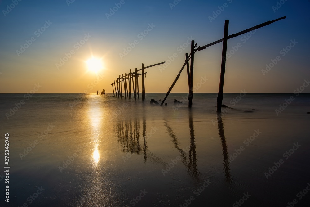 Sunset and reflections from the sea, decaying wooden bridges, Khao Pi Lai Phang Nga beach, Thailand
