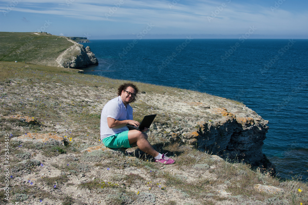 Fototapeta premium Work and vacation. Funny fat man working on the laptop.