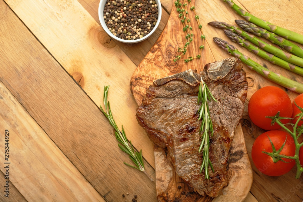 Marbled beef steak on a board with rosemary pepper, spices, and fresh vegetables on a wooden background, restaurant menu, gastronomy, tasty food. Horizontal photo, banner Marbled beef steak on a board with rosemary pepper, spices, and fresh vegetables on a wooden background, restaurant menu, gastronomy, tasty food. Horizontal photo, banner