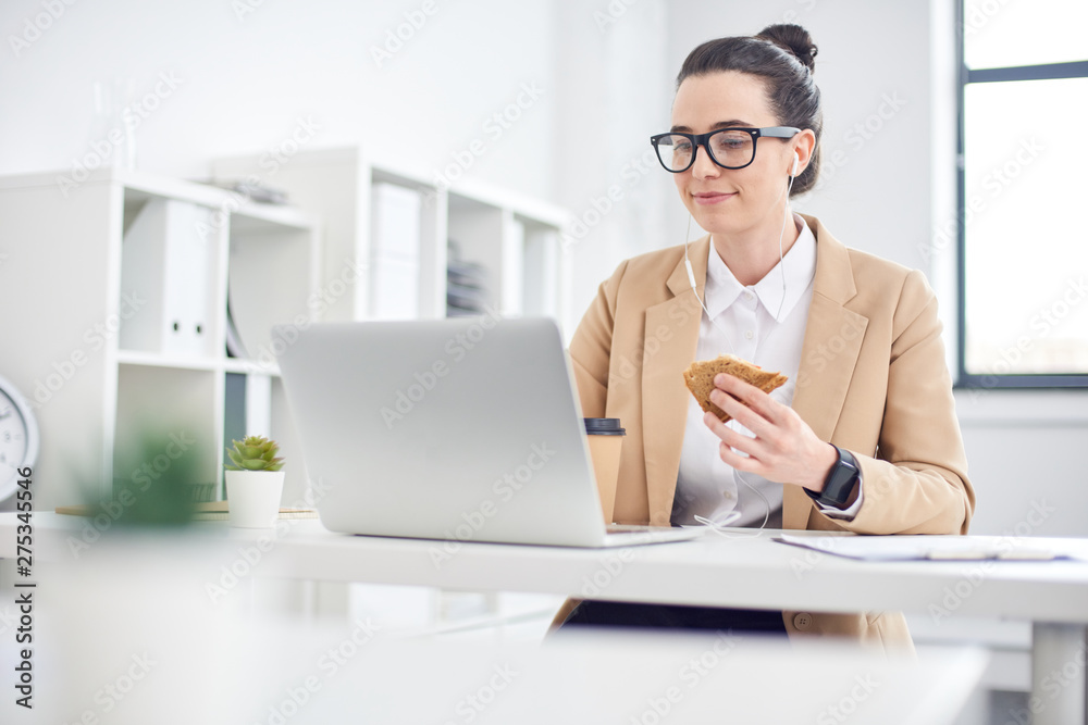 Mid age businesswoman having lunch at laptop in the office Mid age businesswoman having lunch at laptop in the office