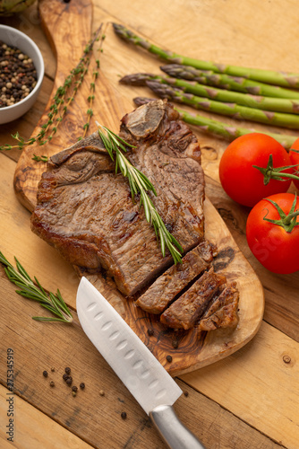 Marbled beef steak on a board with rosemary pepper, seasoning, and fresh vegetables on a wooden background, restaurant menu, gastronomy, tasty food. Restaurant service, verikalnoe photo, banner